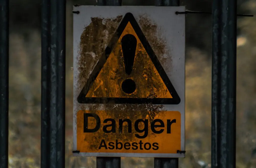 A sign reading “Danger Asbestos” warns individuals of the possibility of asbestos exposure, which can often lead to mesothelioma or other debilitating conditions.