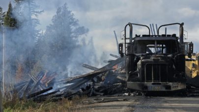 a truck carrying logs that has been in an accident and caught fire