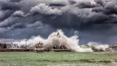 photo of a storm over the ocean. waves crest upon a pier