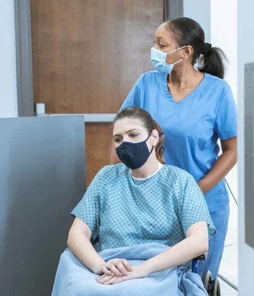 Image of a woman on a wheelchair being assisted by a nurse