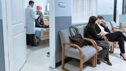 A hospital waiting room with patients sitting in chairs.